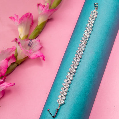 An elegant bracelet with pearl-like beads and a star-shaped cut, displayed on a turquoise background with pink flowers adding a touch of elegance.