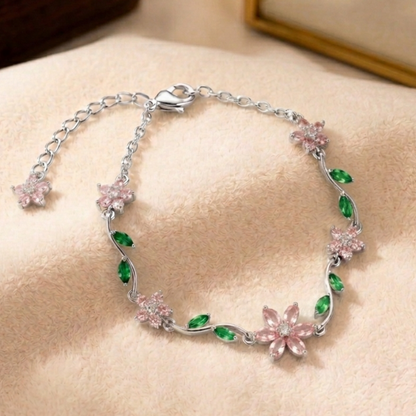Silver bracelet with pink and green floral designs on a beige surface
